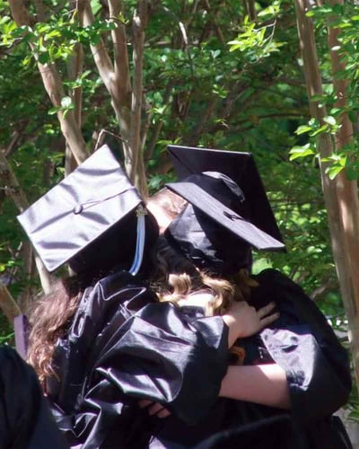 Three friends hug at graduation.