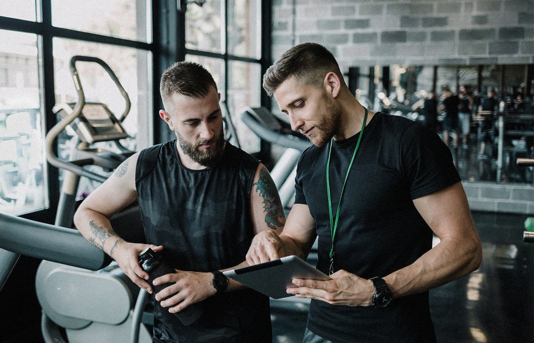 Two trainers review statistics in an exercise gym.